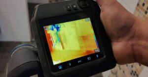 Työmies ottamassa lämpökamerakuvaa kosteista tiloista